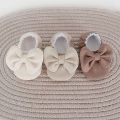 three pairs of baby shoes with bows on them