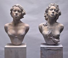 two busturines are sitting on pedestals in front of a gray background and one is wearing a bra