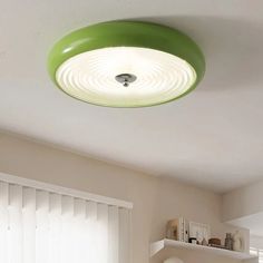 a green ceiling light hanging from the ceiling in a room with white walls and windows