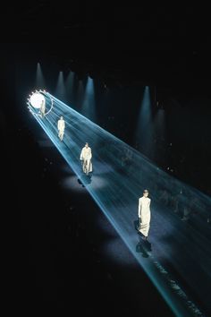 several people are walking down the runway in all white outfits with lights on their heads