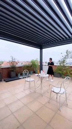 a woman standing on top of a roof next to two white chairs