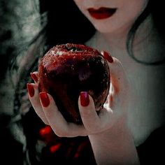 a woman with red nails holding an apple