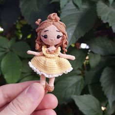 a tiny doll is being held in front of some leaves