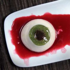 a white plate with a green eyeball in the center and red liquid on it