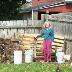 a woman standing next to some buckets in the yard