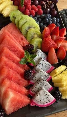 there is a platter of fruit on the table with berries, watermelon, kiwis and grapes