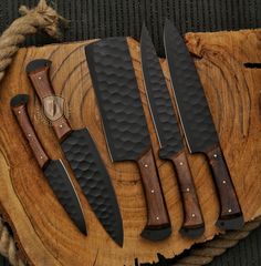 five knives sitting on top of a piece of wood