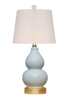 a light blue table lamp with a white shade on the top and gold trim around it