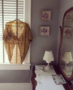 a room with a table, mirror and pictures on the window sill in it