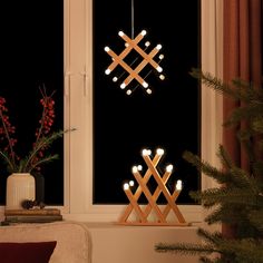 a christmas tree in front of a window with lights hanging from it's branches