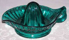 a green glass bowl sitting on top of a white tablecloth with a flower design