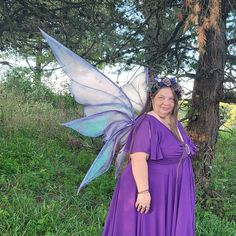 a woman dressed as a fairy standing next to a tree