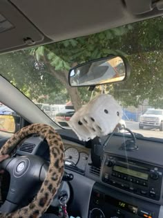 a dog is sitting in the driver's seat of a car with his paw on the steering wheel