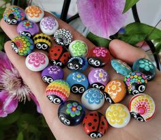 a hand holding a bunch of colorful painted rocks