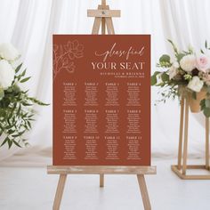 an easel with a seating chart on it and flowers in vases next to it