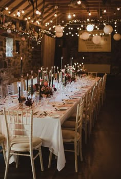 a long table is set with white linens and candles