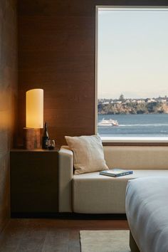 a bed sitting next to a window with a view of the water and buildings in the distance