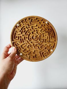 a hand holding a wooden plate with an intricate design on it