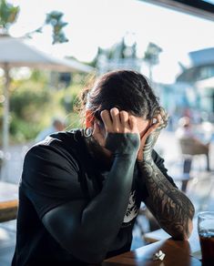 a woman sitting at a table with her hand on her head while talking on the phone