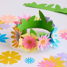 a paper flower crown sitting on top of a table next to some cut out flowers