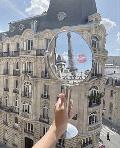 a person holding up a mirror with the eiffel tower reflected in it