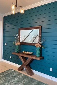 a mirror and vases on a table in front of a blue wall