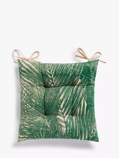 a green pillow with palm leaves on it