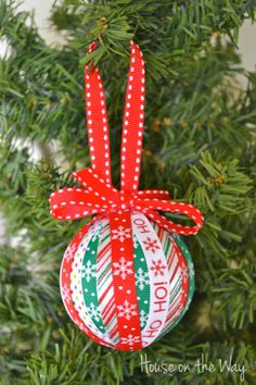 a christmas ornament hanging from a tree with red and green ribbon on it