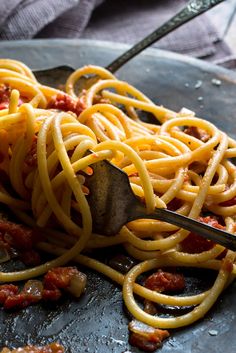 spaghetti being cooked on a pan with a spatula in it and other food items