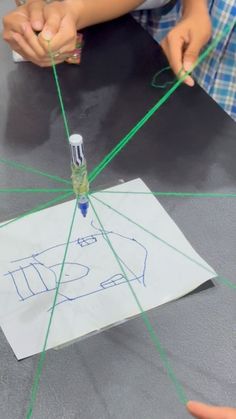 two children are working on something with green thread and glue in front of each other