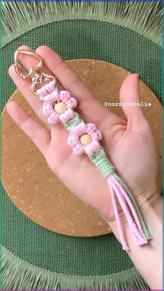 a hand holding a keychain with flowers on it and a tassel hanging from the end