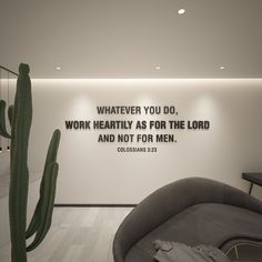 a living room with a cactus in the corner and a quote written on the wall