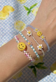 two bracelets with smiley faces on them and beads around the wrist, both decorated with flowers