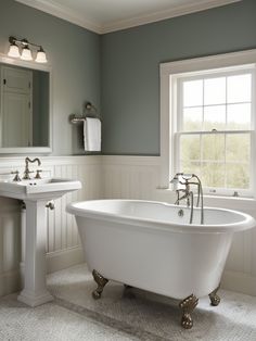 a white bath tub sitting next to a sink under a window in a bathroom with gray walls