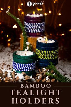 three candles sitting on top of each other in front of snow covered ground and lights