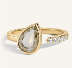 a yellow gold ring with a pear shaped diamond and two smaller diamonds on the band