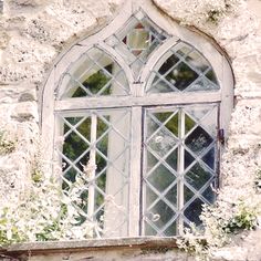 an old stone building with a window and flowers