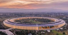 an aerial view of a circular building in the middle of a city with mountains in the background