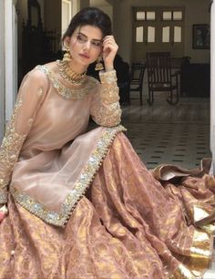 a woman sitting on the floor in a pink dress with gold trimmings and beads