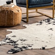 a black and white cowhide rug in a living room with blue leather chair and ottoman