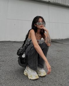 a woman sitting on the ground wearing sunglasses