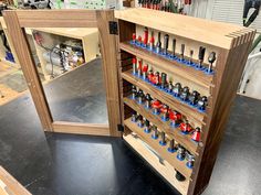 an open cabinet with tools in it on top of a black table and some shelves