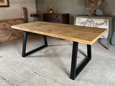 a wooden table with black metal legs in a room next to a busturine