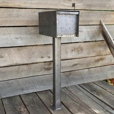 a metal post on the side of a wooden building with a bird feeder in it