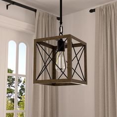 a light fixture hanging from the ceiling in a room with curtains and window behind it