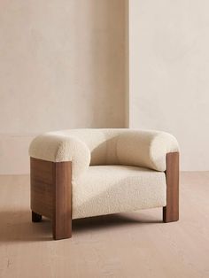 a white chair sitting on top of a wooden floor next to a tall wall in an empty room