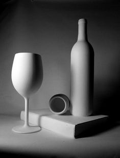 black and white photograph of two wine glasses, one empty bottle and the other half full