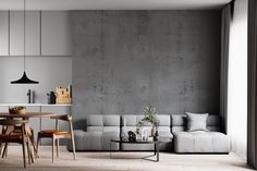 a living room with a couch, table and chairs in front of a concrete wall