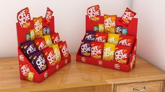 two red boxes filled with different types of candy on top of a wooden table next to each other