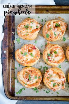 several mini pizzas with cheese and herbs on a baking sheet, ready to go into the oven